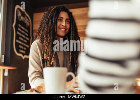 Donna sorridente seduto in un ristorante a parlare con il suo amico. Amici seduti in un caffè con caffè sul tavolo. Foto Stock