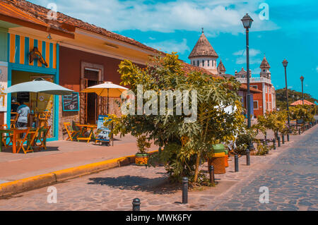 GRANADA, NICARAGUA - Aprile 28, 2016: Outdoor View di ristoranti in un coloniale e bellissimi edifici colorati in una fila nella città con alcune sedie unbrella turistico per mangiare Foto Stock