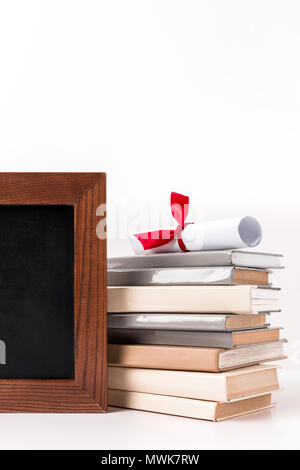 Diploma sulla pila di libri con lavagna vuota isolata su bianco Foto Stock