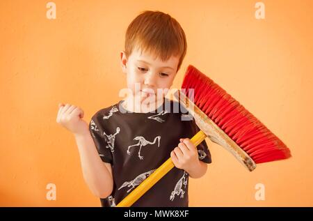 Piuttosto Caucasian bambino con una scopa, casa stock immagine. Madre di little helper, pulizia, pulizia del concetto di camera. Foto Stock