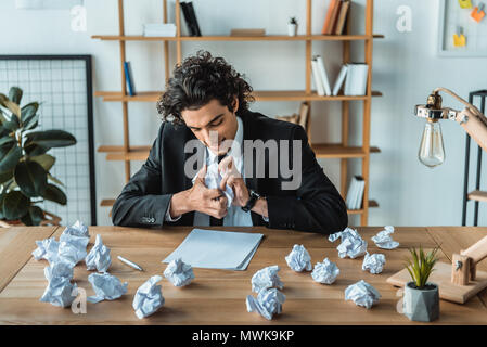 Ritratto di angry businessman sgualcimento documenti al lavoro in ufficio Foto Stock
