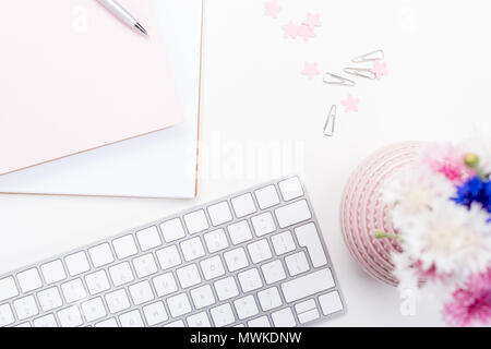 Vista dall'alto della tastiera, notebook con penna, fiori e delle forniture di ufficio al lavoro Foto Stock