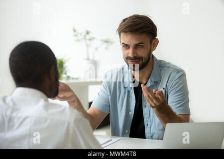 Sorridente lavoratore caucasica parlando a nero collega in ufficio Foto Stock