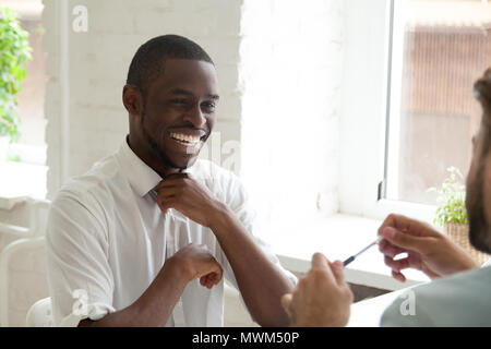 Sorridente americano africano di ridere mentre parla a un collega Foto Stock