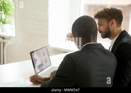 Diversi lavoratori analizzando i rapporti finanziari al computer portatile in ufficio Foto Stock
