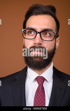 Giovane bello barbuto imprenditore persiano contro backgro marrone Foto Stock