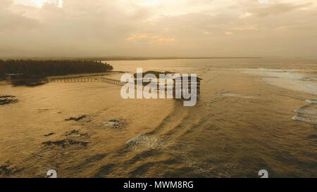 Punto di vista nell'oceano al Cloud Nine punto surf al tramonto, Siargao island , Filippine. Vista aerea sollevata passerella in legno per surfisti di attraversare la barriera corallina di siargao island al cloud 9 surf break sull isola di Mindanao. Isole Siargao famoso surf break cloud 9. Volare sopra il mare blu nelle acque azzurre della laguna. Foto Stock