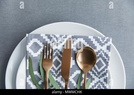 Lay piatto con tavolo rustico con impostazione vintage opacizzato argenteria, igienico, piante verdi e la piastra Foto Stock