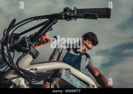 Repairman nella riparazione di occhiali vintage motociclo fuori Foto Stock