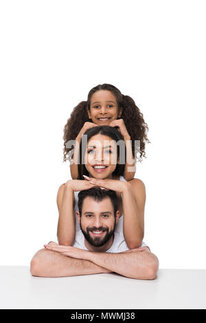 Felice famiglia multietnica appoggiata al tavolo bianco e sorridente in telecamera Foto Stock