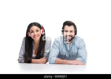 Felice coppia giovane che indossa le cuffie e sorridente in telecamera isolato su bianco Foto Stock
