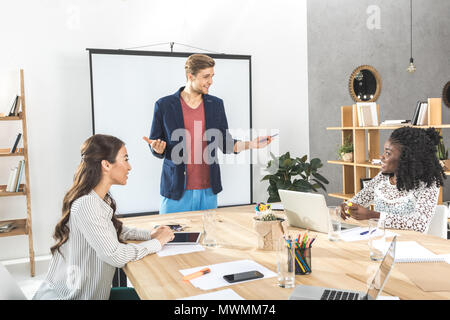 Giovane imprenditore rendendo presentazione per i colleghi alla riunione in ufficio Foto Stock