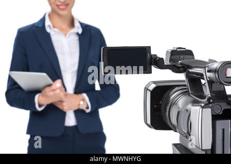 Vista ritagliata della newscaster con tavoletta digitale in piedi nella parte anteriore della fotocamera, isolato su bianco Foto Stock