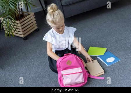 Angolo di alta vista di carino little schoolgirl con zaino la preparazione per la scuola Foto Stock