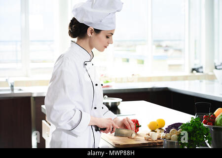 Femmina professionale chef ingredienti di taglio per il piatto Foto Stock