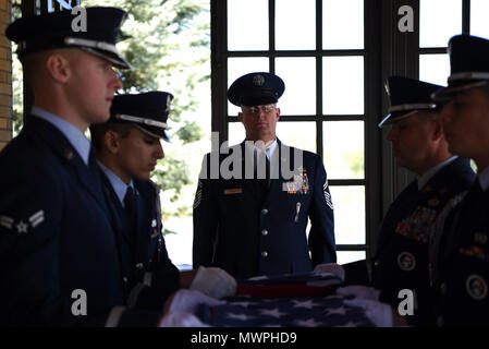 Senior Master Sgt. Brett Kitzman, centoquarantesimo Gruppo di manutenzione degli aeromobili Sistemi di armamento soprintendente, sorge a attenzione mentre i membri del miglio alta la guardia d'onore piegare la bandiera durante un funerale militare onore, apr. 28, 2017 a Fort Logan Cimitero Nazionale Kitzman Colo., che ha lavorato con il defunto in passato, volontariamente di partecipare al servizio e a presentare al tri-fold flag per i parenti prossimi. Foto Stock