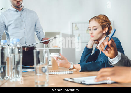 Immagine ritagliata di imprenditori multiculturale seduto alla riunione in ufficio Foto Stock