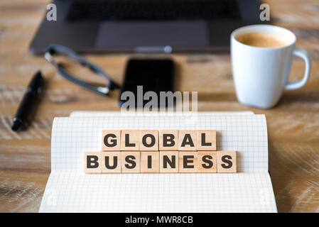 Primo piano su notebook su tavola di legno sfondo, concentrarsi sui blocchi di legno con lettere Making Global Business testo. Foto Stock