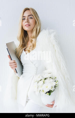 Moda elegante imprenditrice con il computer portatile e i fiori bianchi a luce moderno ufficio Foto Stock