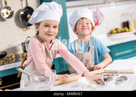 Bambina e ragazzo chef hat e grembiule cucinare uova fritte