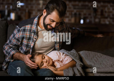 Piccola figlia addormentarsi sulle ginocchia di padri a casa Foto Stock