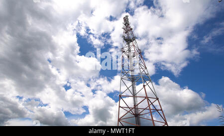Telefono cellulare la torre contro un cielo blu. Torre di comunicazioni con un sacco di diverse antenne sotto il cielo blu e nuvole. Torre di telecomunicazione con l'azzurro del cielo. Foto Stock