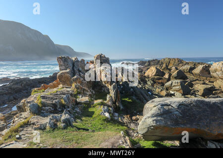 Formazioni di roccia sporgente nell'oceano indiano a Tsitsikamma, area protetta, Garden Route, Cape, Sud Africa Foto Stock