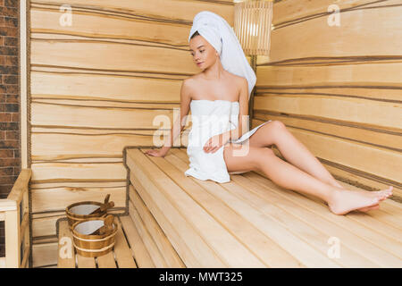 Bella giovane donna rilassante sul banco a sauna Foto Stock