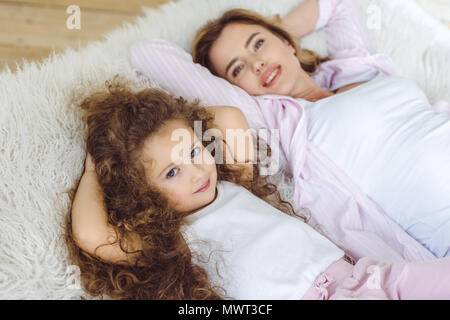 Felice la figlia e la madre bella giacente sulla pelle di pecora coperta Foto Stock