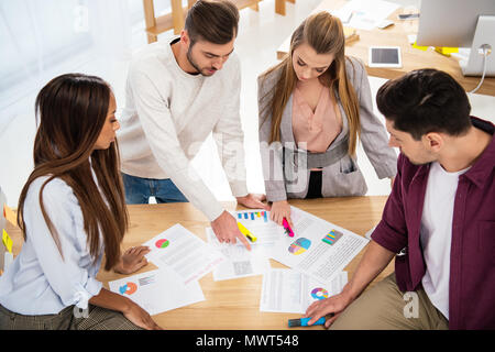 Multietnica di colleghi di lavoro per discutere il nuovo progetto di marketing al lavoro in ufficio Foto Stock