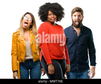 Gruppo di tre giovani uomini e donne sentirsi disgustato con la lingua di fuori Foto Stock