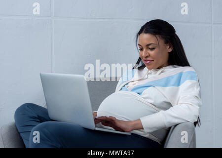 Bella americano africano donna incinta utilizzando laptop Foto Stock