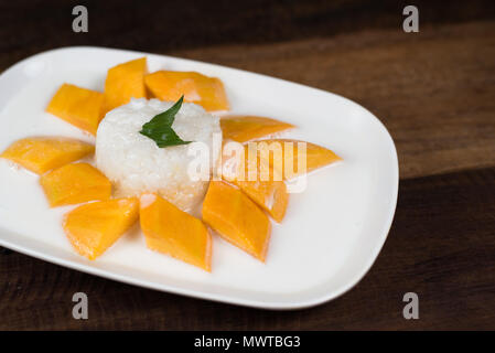 Mango riso appiccicoso o Khaoniao mamuang su un tavolo di legno, un tradizionale Thai dessert fatti con riso glutinoso,mango fresco e latte di cocco Foto Stock