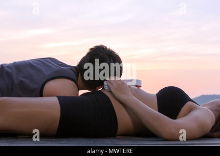 Donna incinta mettendo le cuffie sul ventre e uomo ascoltare musica sul piano al tramonto di montagna, tempo di attesa concept Foto Stock