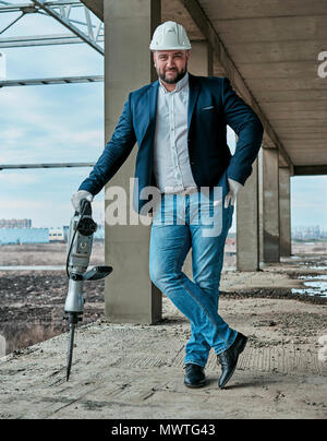 Uomo in un casco sul sito in costruzione Foto Stock