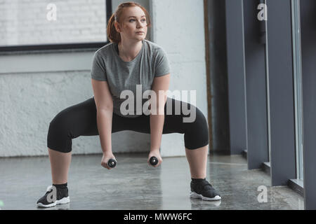 Curva ragazza il sollevamento pesi in palestra Foto Stock