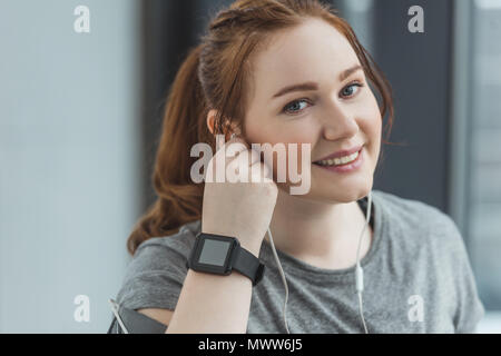 Ragazza obesi con fitness tracker ascoltando musica in palestra Foto Stock