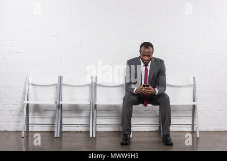 African American businessman con lo smartphone in attesa per il colloquio di lavoro Foto Stock