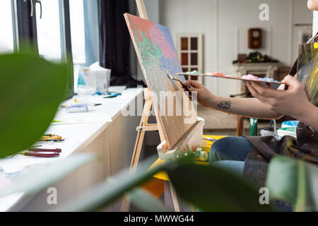 Vista ravvicinata del giovane ragazza creativo l'applicazione di primer su tela in studio di luce Foto Stock