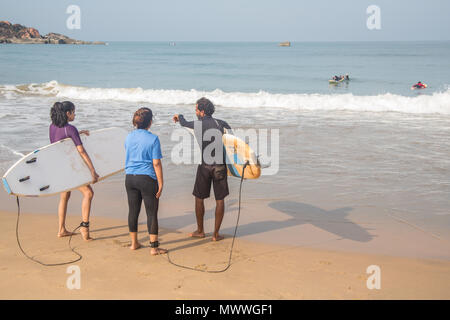 Gli studenti di Surf salire in acqua in una spiaggia a Goa, India, durante un inizio sessione estiva. Foto Stock