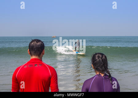 Navigare gli studenti guardando l'istruttore surf onda. Foto Stock