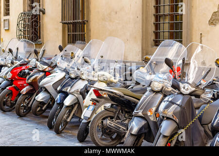 Una tipica strada di Firenze con moto scooter parcheggiati in fila in Italia Foto Stock