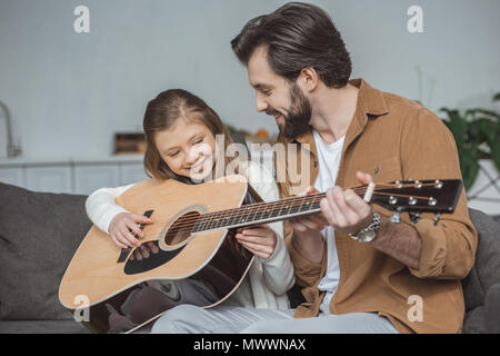 Felice padre figlia di insegnamento suonare la chitarra acustica Foto Stock