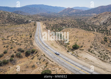 Unica vettura sul deserto vuoto strada nel deserto di Mojave della California del sud. Foto Stock