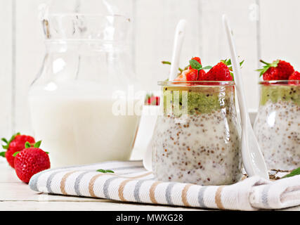 Detox e sana colazione superfoods in barattolo. Vegano latte di cocco semi di chia pudding con fragole e kiwi. Foto Stock