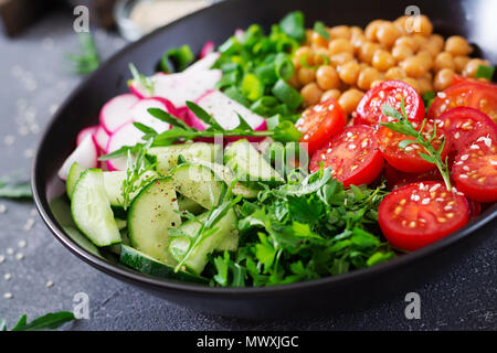 Insalata di ceci, pomodori, cetrioli, ravanello e verdi. Integratori alimentari. Ciotola di Buddha. Vegan insalata. Foto Stock