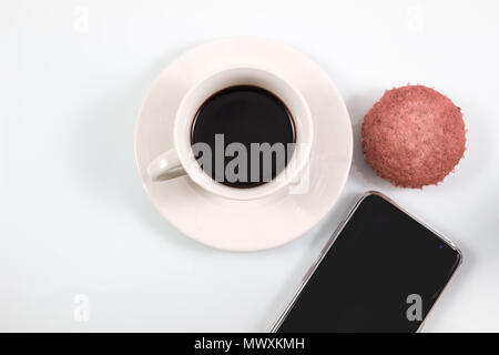 Vista superiore, caffè espresso in tazza bianca con fatti in casa muffin brownie torte e lo smartphone isolati su sfondo bianco, coffee break nel concetto di soft Foto Stock