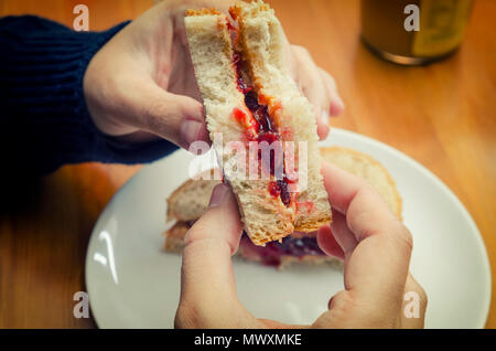 Mangiare un panino con burro di arachidi e marmellata di ciliege Foto Stock