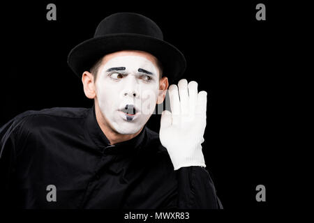 Mime overhearing qualcosa di isolato su nero Foto Stock