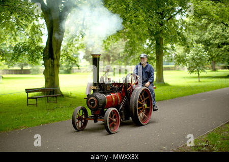 Un uomo aziona il suo motore a vapore giù per un sentiero a Himley Hall vintage fair a Dudley, West Midlands. Foto Stock